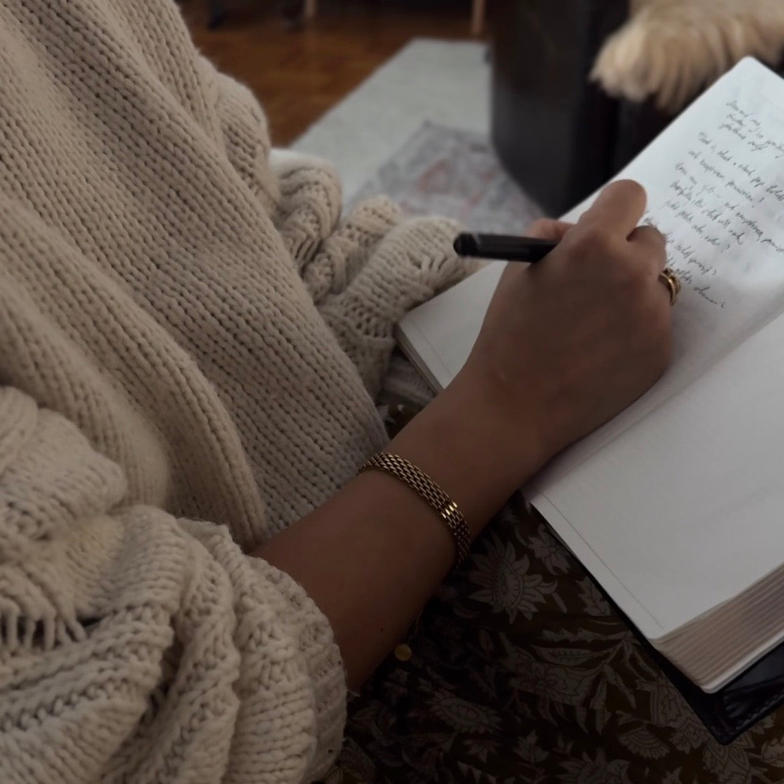 Person writing in a notebook by hand in a quiet, warm setting